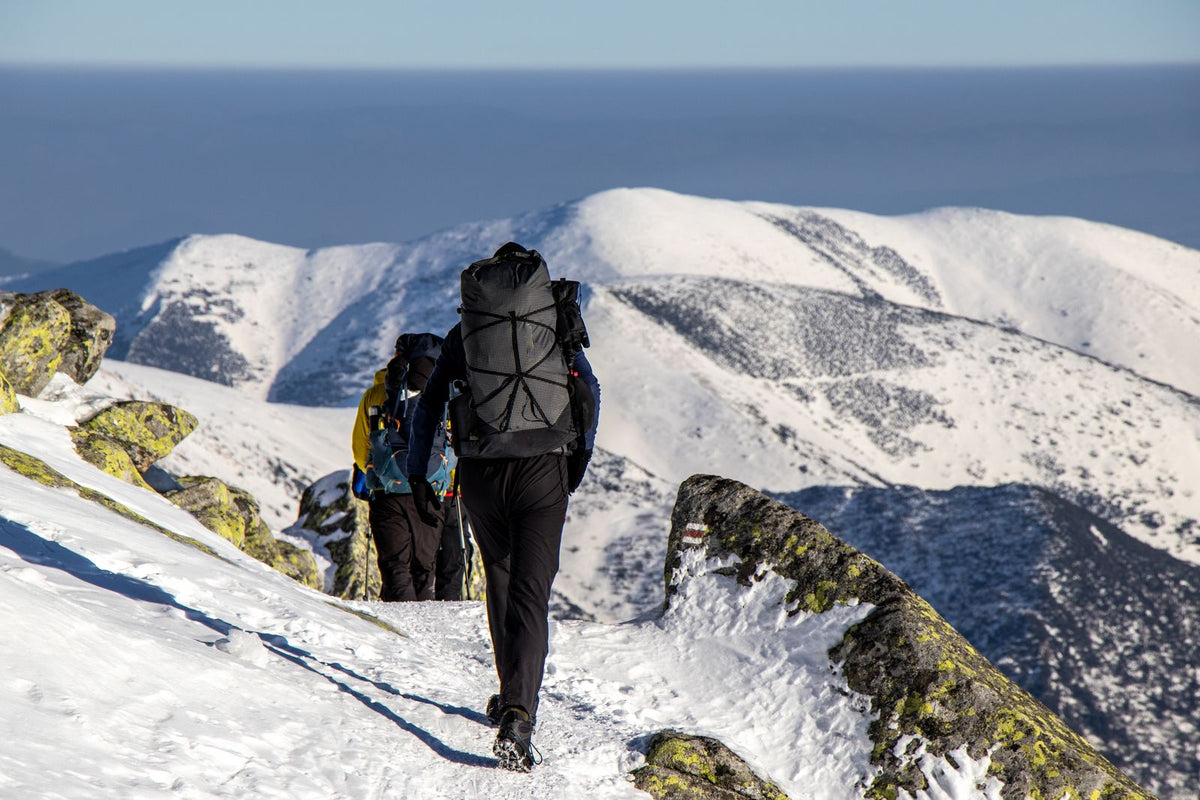 Hikers in full winter gear trekking through a snowy mountain landscape