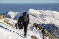 Hikers in full winter gear trekking through a snowy mountain landscape