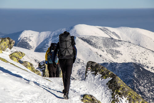 Hikers in full winter gear trekking through a snowy mountain landscape